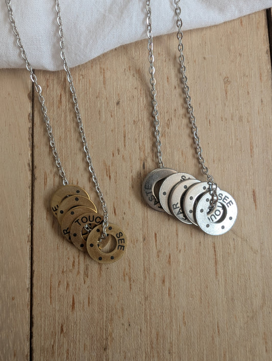 Necklaces shown in brass and stainless steel. Pendants have anxiety relief grounding framework printed on them. 