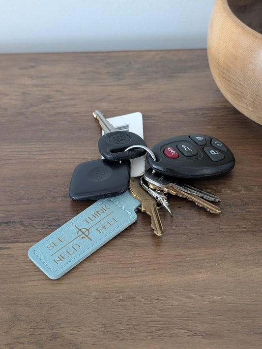 Keys with a leather communication keychain on a wooden surface