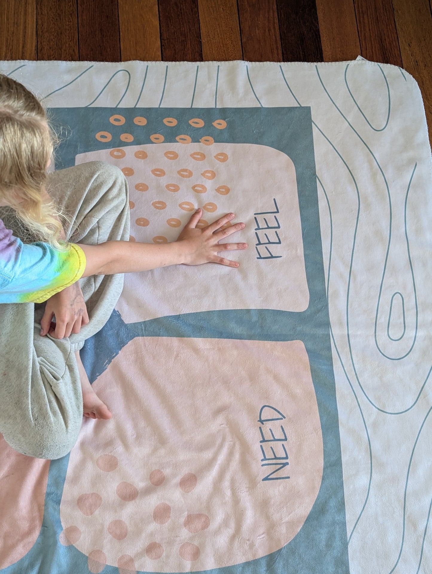 Child interacting with a communication blanket with the emotional regulation (see-think-feel-need) framework displayed. 
